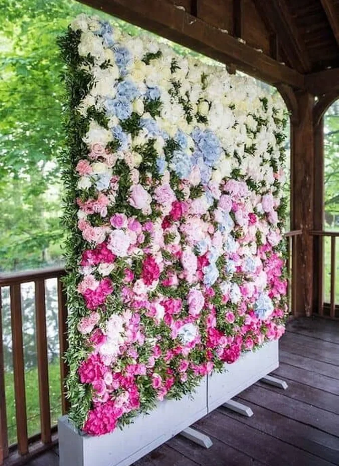 Greenery wall photo booth backdrop with wedding sign at an outdoor wedding