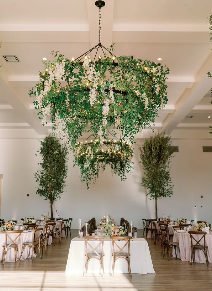Hanging greenery chandelier with trailing plants suspended over a wedding aisle