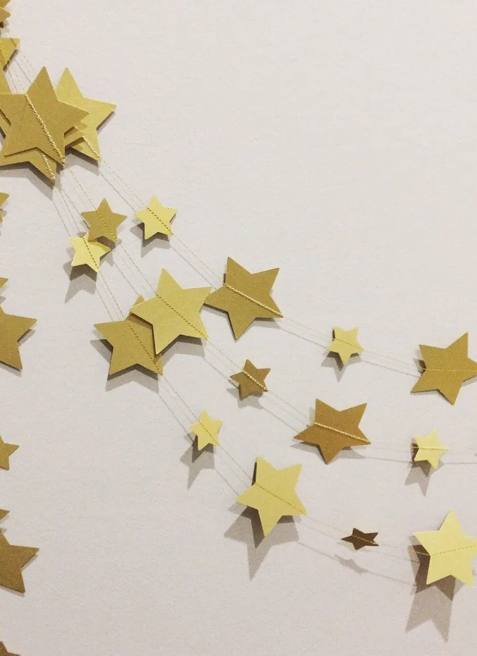 Gold star cutouts scattered on a dark wall with a graduate name sign