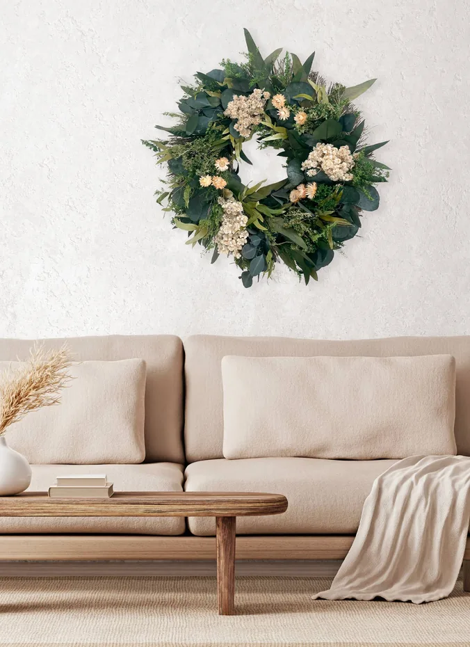 Round green eucalyptus wreath hanging centered above a sofa