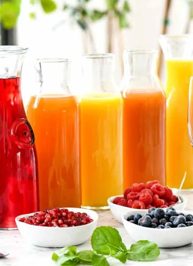 Mimosa bar with labeled glass carafes of juice on table