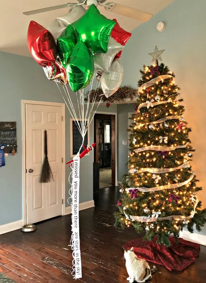 Elf on the shelf with colorful balloons staged by a door