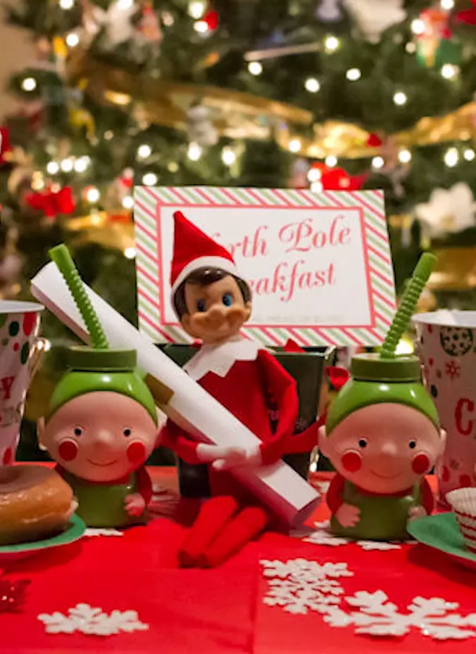 Elf on the shelf at a North Pole breakfast table with donuts