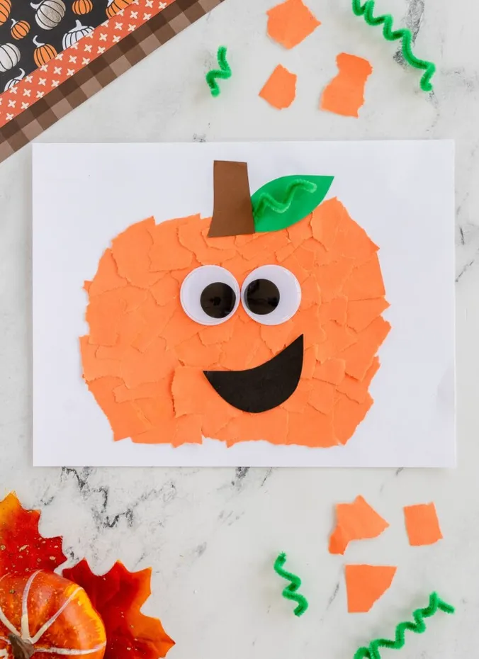 Torn orange paper pumpkin collage with googly eyes and a smile