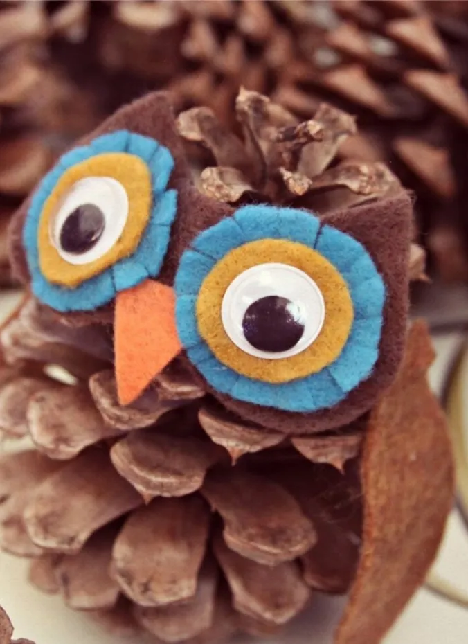 Pinecone owl craft with felt eyes and beak made by kids