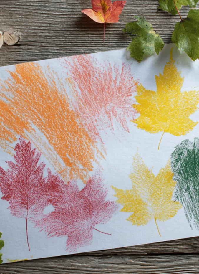 Crayon leaf rubbings in orange red and yellow on white paper