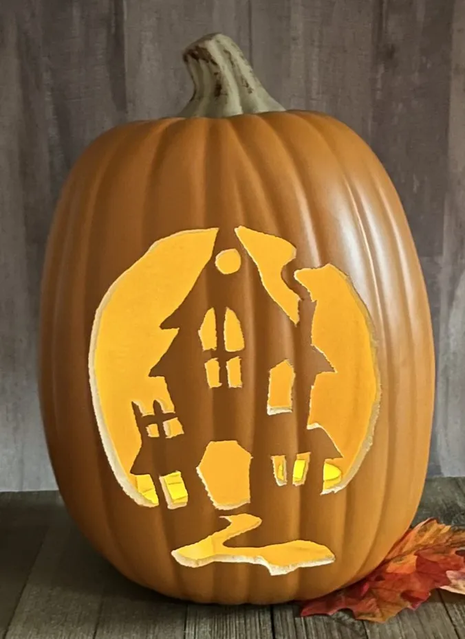 Decorated foam pumpkin with a glowing haunted house design