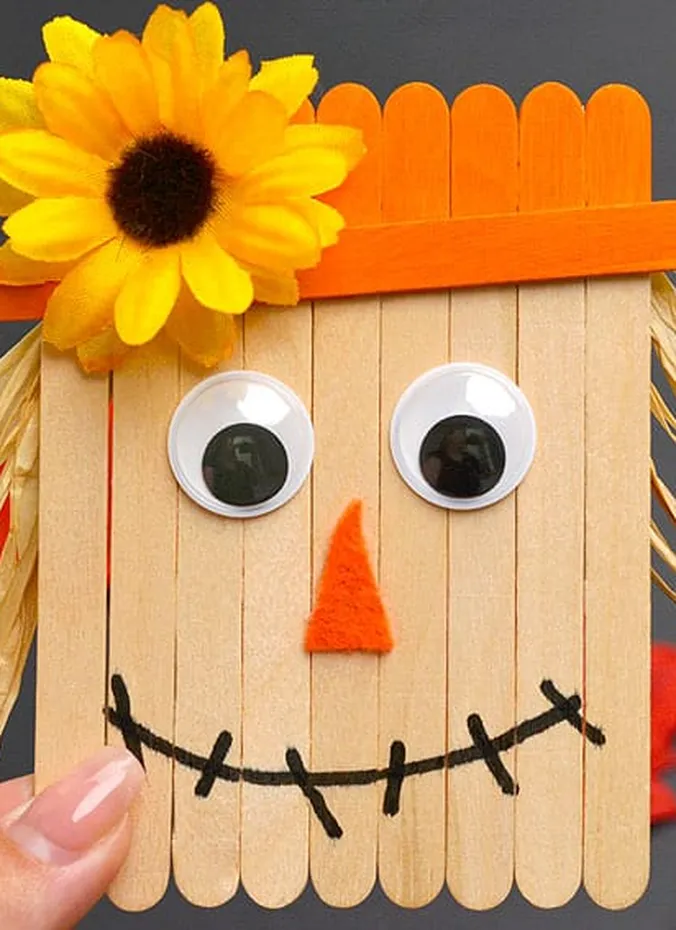 Popsicle stick scarecrow craft with painted hat and googly eyes