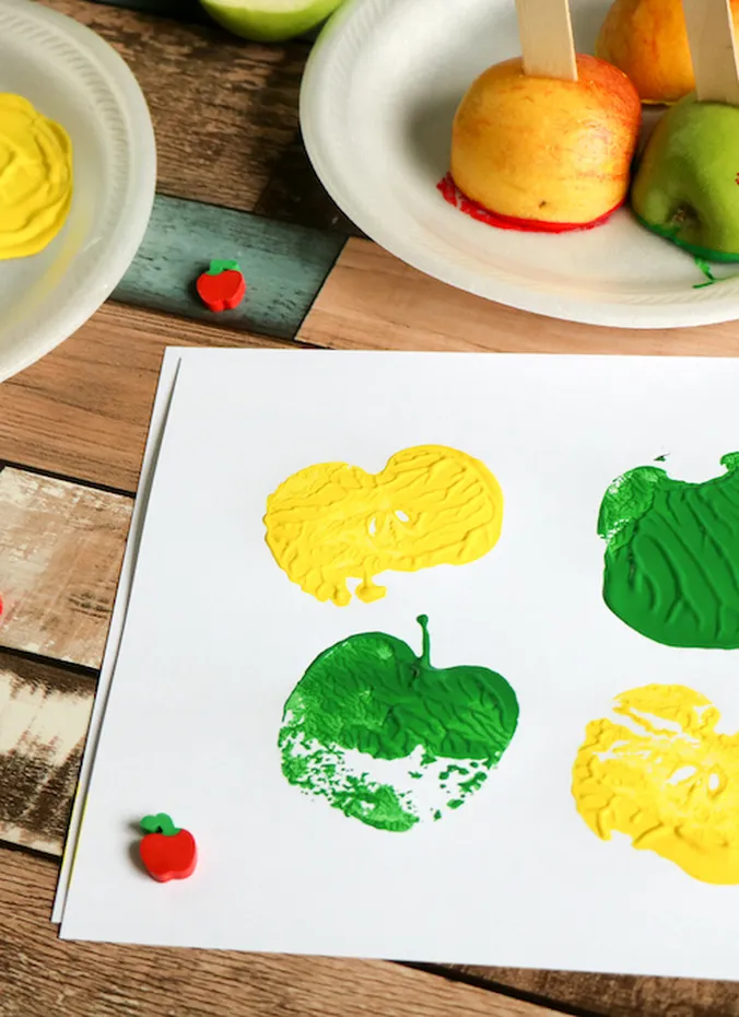 Apple stamping art with green and yellow apple prints on paper