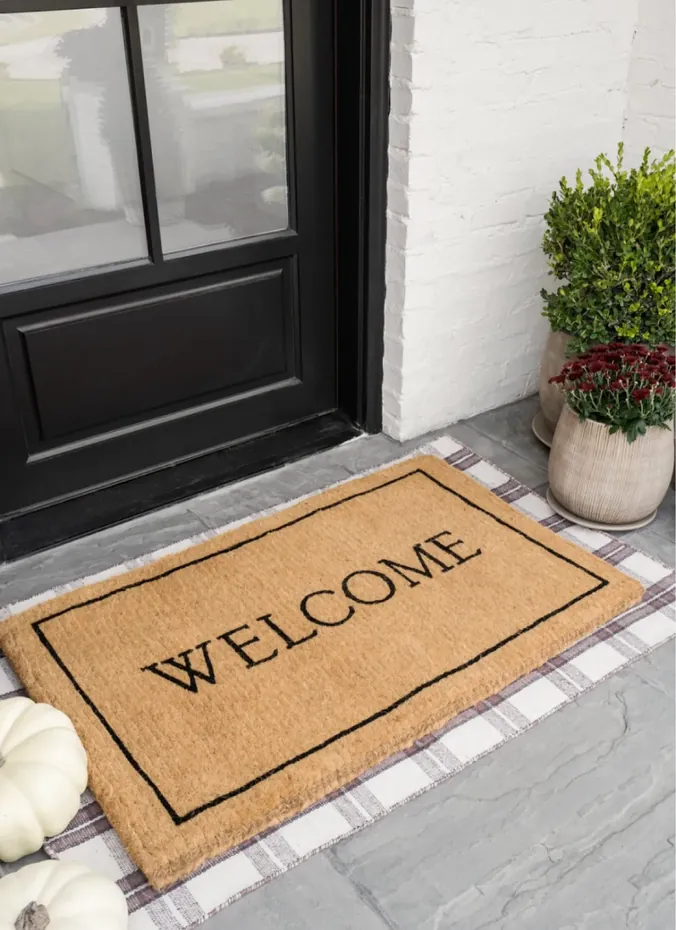 Layered doormat with fall styling at a front door