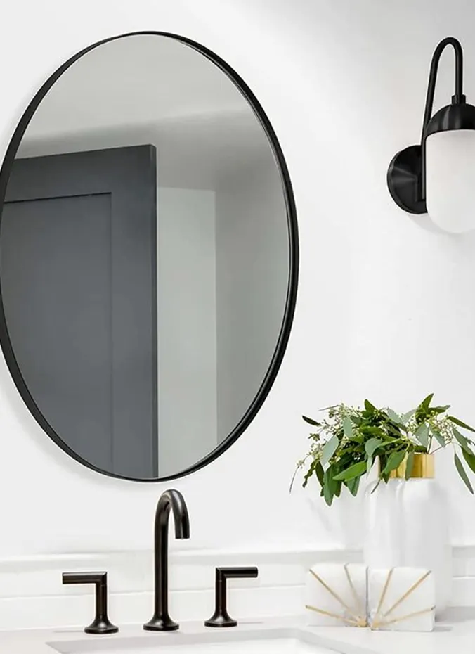 Black gooseneck wall sconce beside a round bathroom mirror