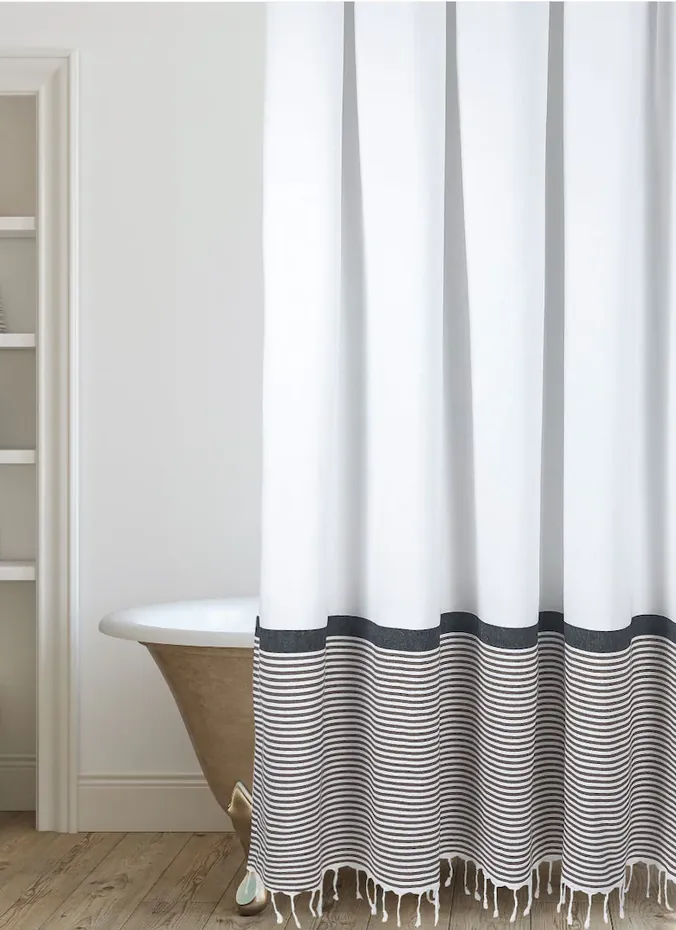 Striped fabric shower curtain with tassels in a farmhouse bathroom