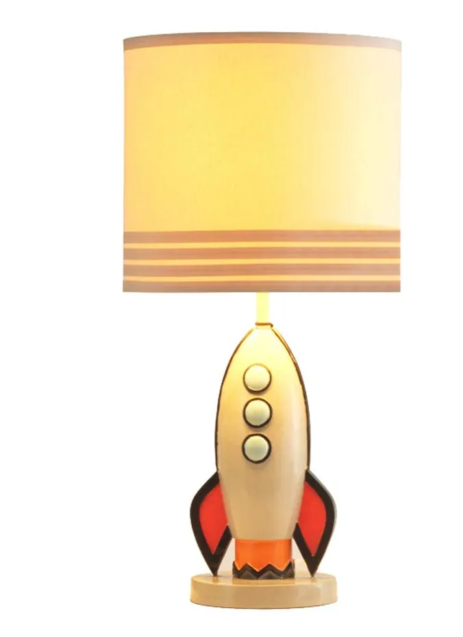 Rocket ship table lamp with blue base on a wooden nightstand