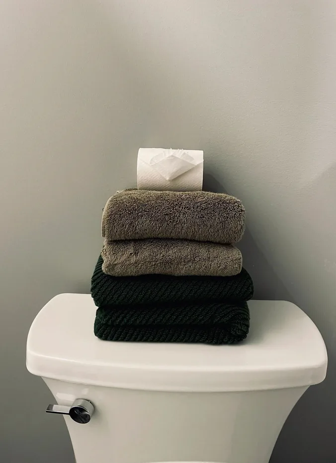 Stack of neatly folded colorful hand towels on a toilet tank