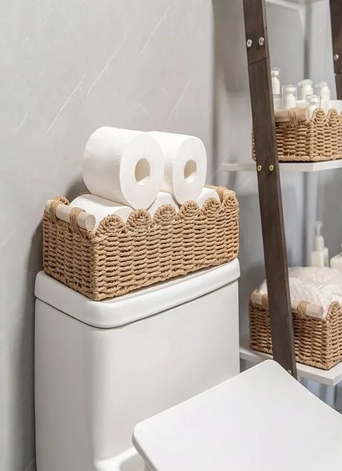 Extra toilet paper rolls styled in a small holder on a toilet tank