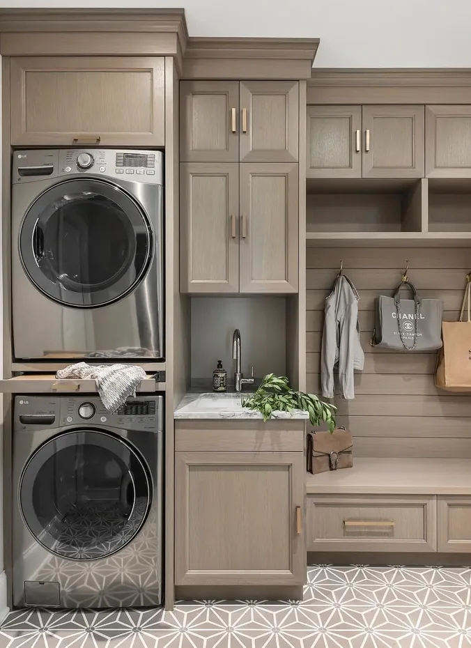 Stacked washer and dryer in a mudroom corner with storage